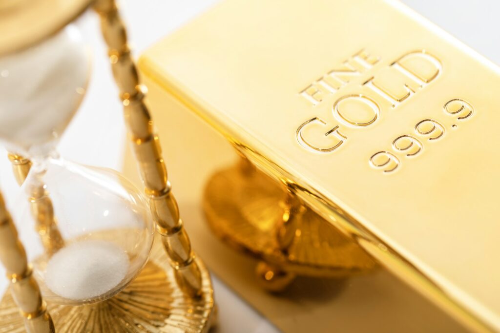 Hourglass and fine gold bullion. Concept of investment.